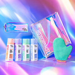 A beauty gift set from both sides featuring Technocolor hair products, including four spray bottles, a holographic makeup pouch, a large holographic tote bag, and a mint green silicone oven mitt, arranged on a vibrant, multicolored light streak background.
