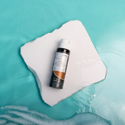 Skincare bottle on a white square with a blue water background
