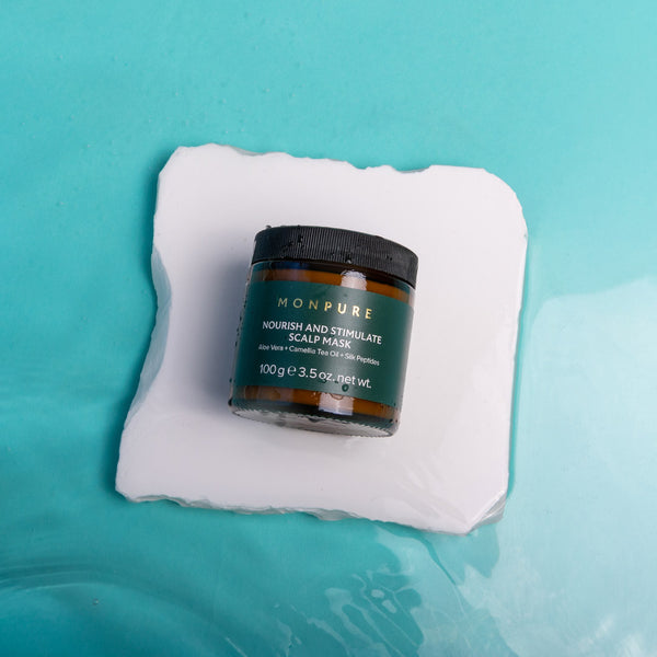 Jar of Monpure scalp mask on a white towel with a blue background