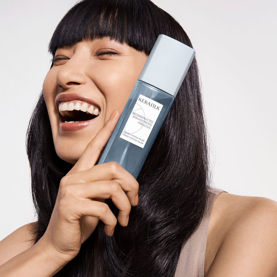 Woman holding a bottle of KERASILK hair product with a white background