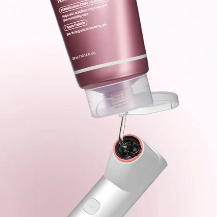 Close-up of a skincare device with a pink container on a light pink background