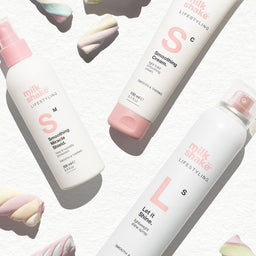 Three bottles of 'milk shake' hair care products with colorful cookies in the background.