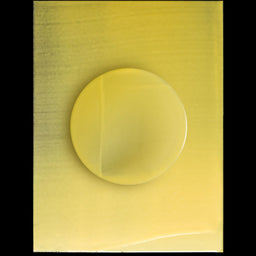 A translucent yellow circular gel or liquid drop centered on a square yellow sample card, photographed against a black background.