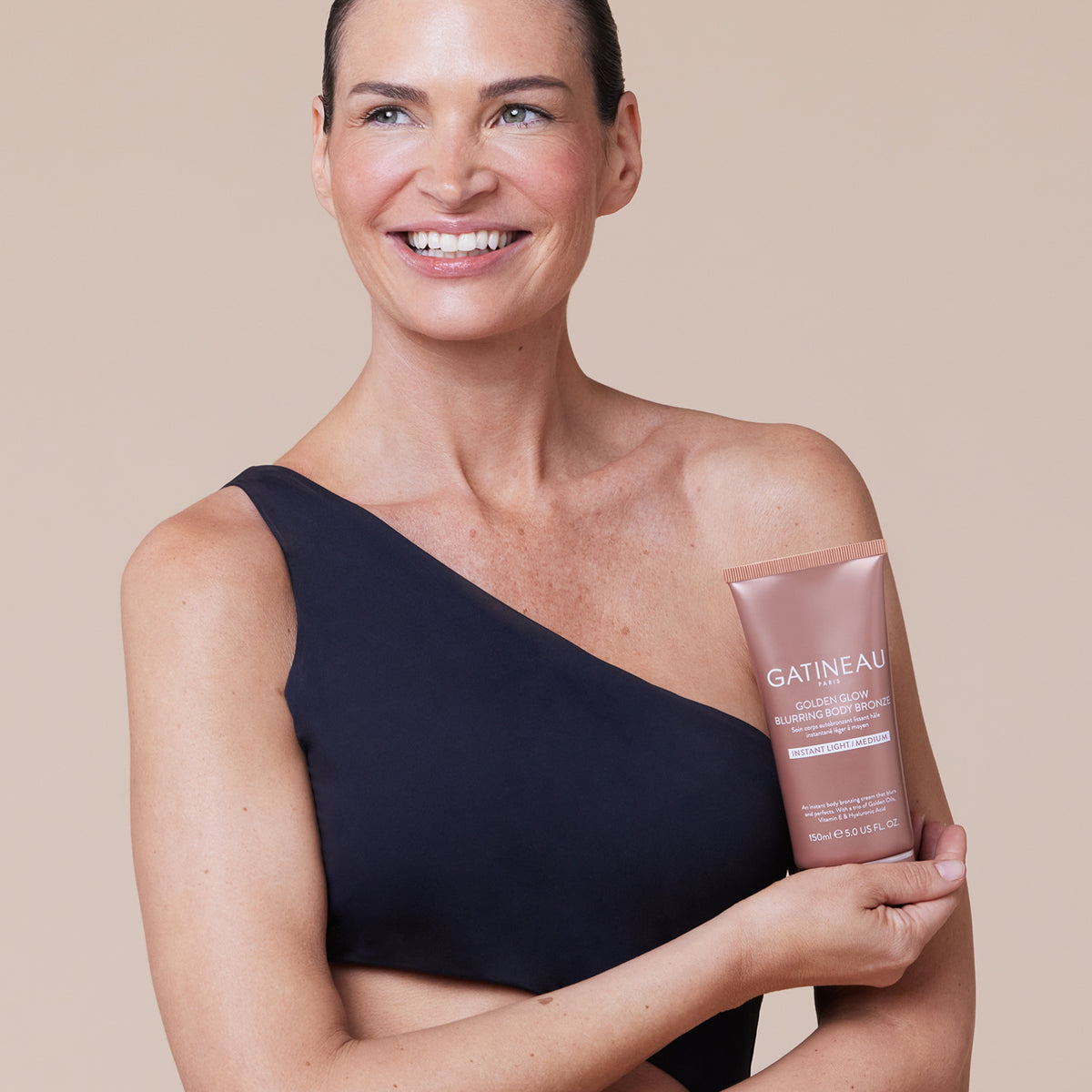 Woman holding a Gatineau product against a beige background