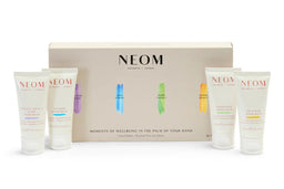 NEOM Moments of Wellbeing in the Palm of Your Hand gift set, featuring a beige presentation box with four small white hand cream tubes arranged in front on a white background.