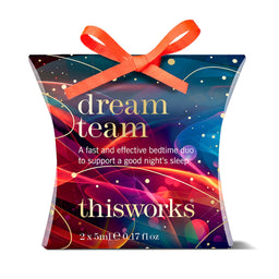 A square gift box for a sleep aid product on a white background. The box is dark blue and purple with abstract glowing line art, gold text reading 'dream team' and 'thisworks', and an orange ribbon tied around the top.