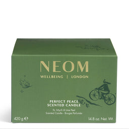 A green rectangular box of NEOM Wellbeing London 'Perfect Peace' scented candle, featuring gold lettering and a black line art illustration of a cyclist, set against a plain white background.