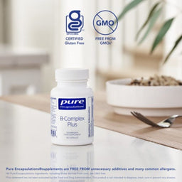 A bottle of Pure Encapsulations B-Complex Plus dietary supplement capsules, set on a wooden table with a blurred bowl and spoon in the background. Two badges at the top indicate 'Certified Gluten Free' and 'Free From GMOs'.