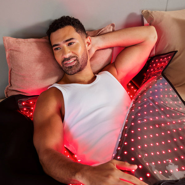 Man lying on a bed with LED pillows emitting red light