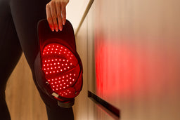 Person holding a red light cap, glowing red, reflected on nearby surface 