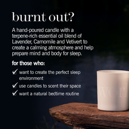 A white ceramic candle jar sits on a rustic wooden surface against a dark, atmospheric background. White text on the image reads 'burnt out?' and describes a hand-poured candle with lavender, camomile, and vetiver essential oils for a calming sleep atmosphere.