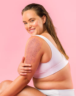 Model applying Sand & Sky Australian Pink Clay Smoothing Body Sand to her arm and shoulder