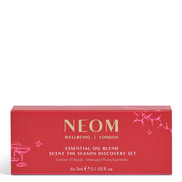 A red rectangular box for NEOM Wellbeing London 'Scent the Season Discovery Set' with gold and pink text and line illustrations, photographed on a plain white background.