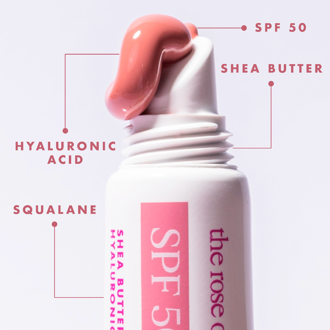 Lip balm with SPF 50 labeled, featuring shea butter, hyaluronic acid, and squalane on a light pink background.