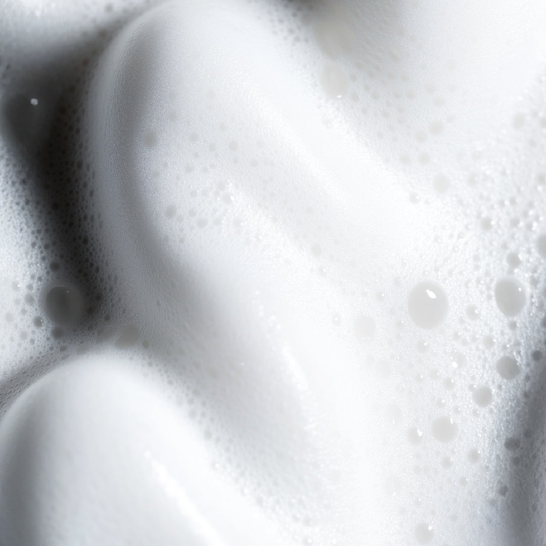 Close-up of thick, white lather or foam with fine bubbles and soft shadows.