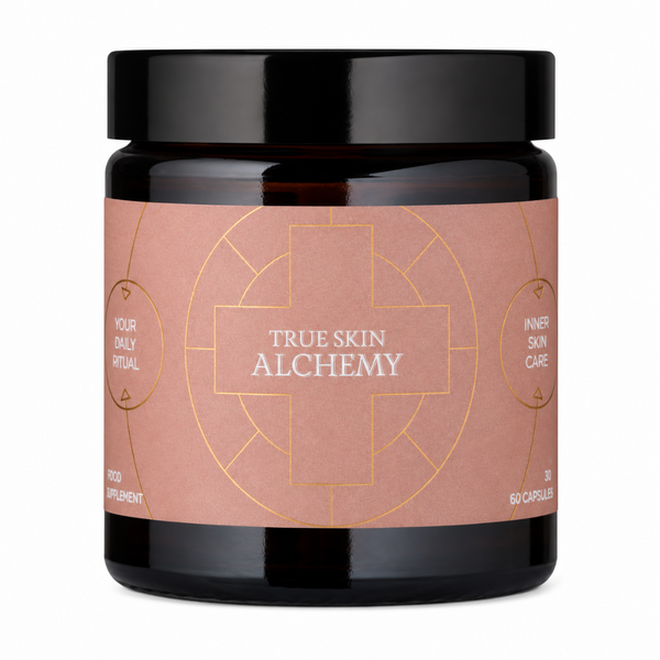A black supplement jar with a black lid and a dusty rose label featuring gold geometric line art and the text 'TRUE SKIN ALCHEMY' and 'YOUR DAILY ALCHEMY'.