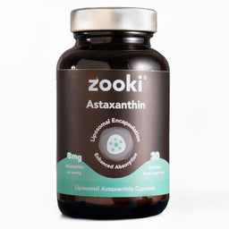 A bottle of Zooki Astaxanthin dietary supplement capsules. The product is in a dark amber brown bottle with a metallic silver cap and a dark brown label featuring a teal accent band and white text.