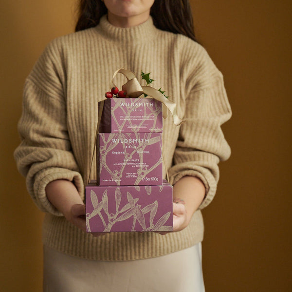 Person holding Wildsmith skin care boxes against a brown background