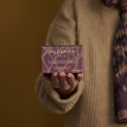 Person holding a Wildsmith Skin product against a blurred background