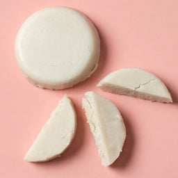 White macaron with three slices on a pink background