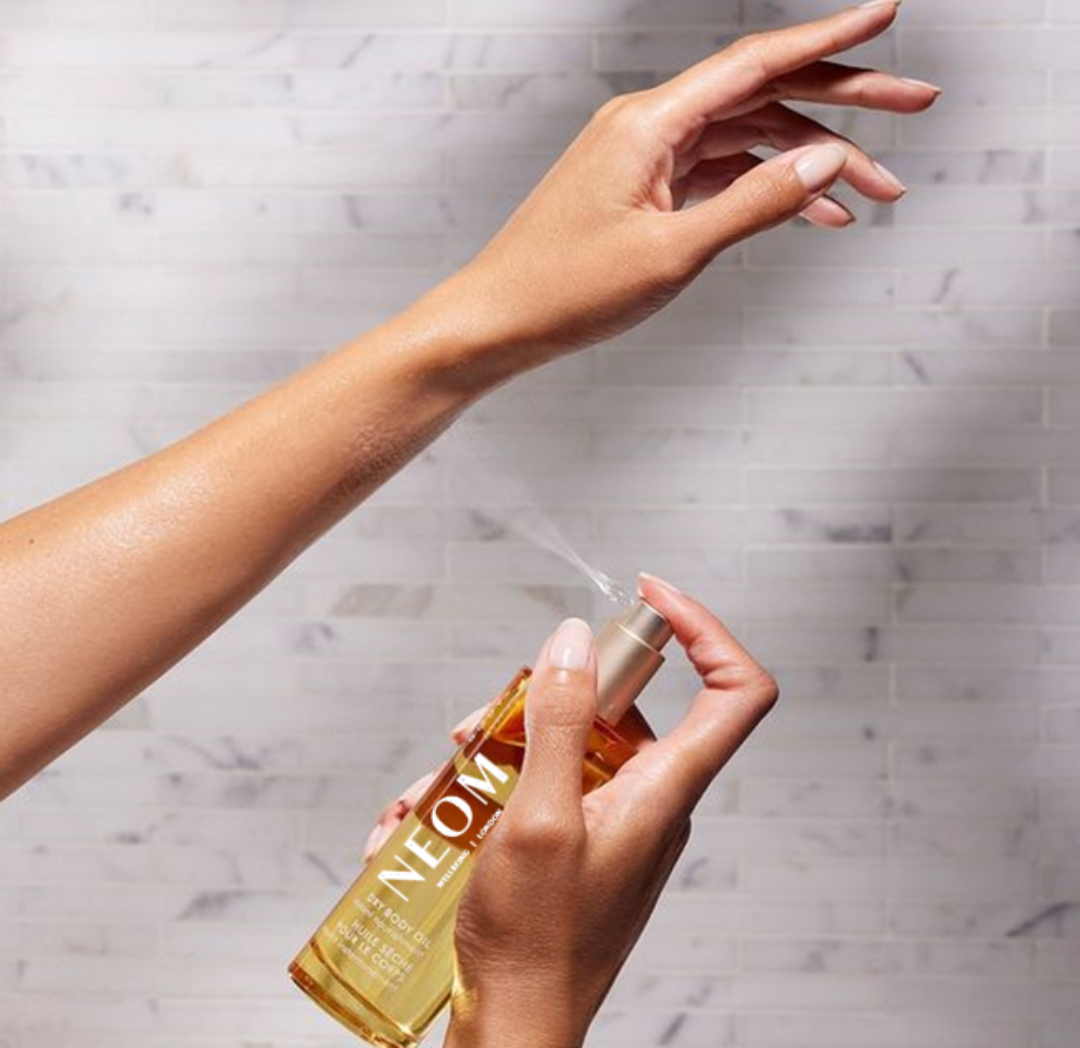 Person using a gold bottle labeled 'NEOU' with a marble background
