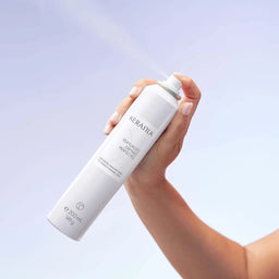 Hand holding a Kerastilik hair product bottle against a light purple background