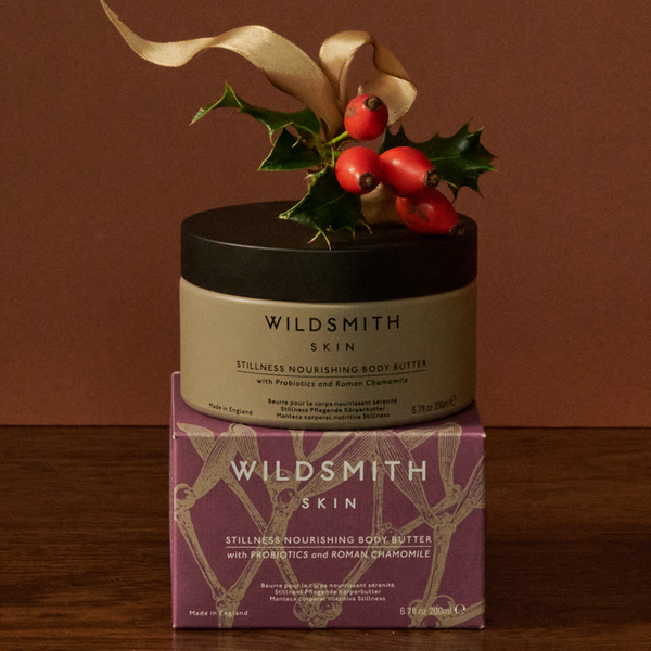 Wildsmith Skin body butter with holly leaves on a brown background