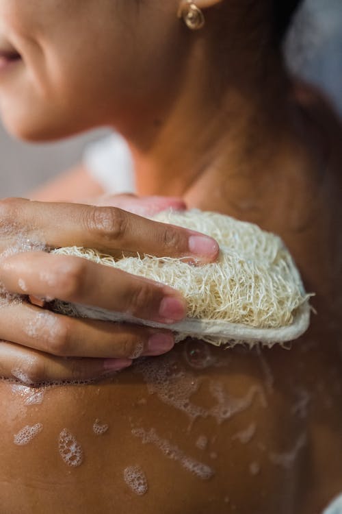 a woman scrubbing her shoulder with a scrub 