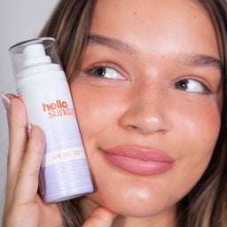 a closeup of a women holding a bottle of Hello Sunday The Retouch One - Face Mist SPF30 close to her face