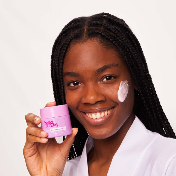 a closeup of a women smiling with Hello Sunday The Recovery One Glow Face Mask on her cheek 