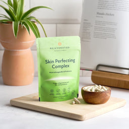 Rejuvenated Skin Perfecting Complex on a chopping board with a small cup of capsules