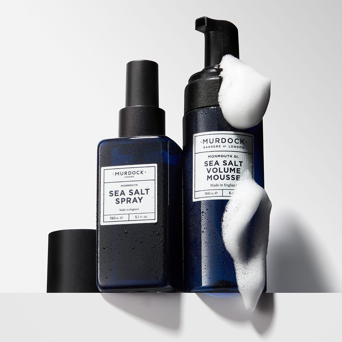 two bottles of murdock london products covered in soap